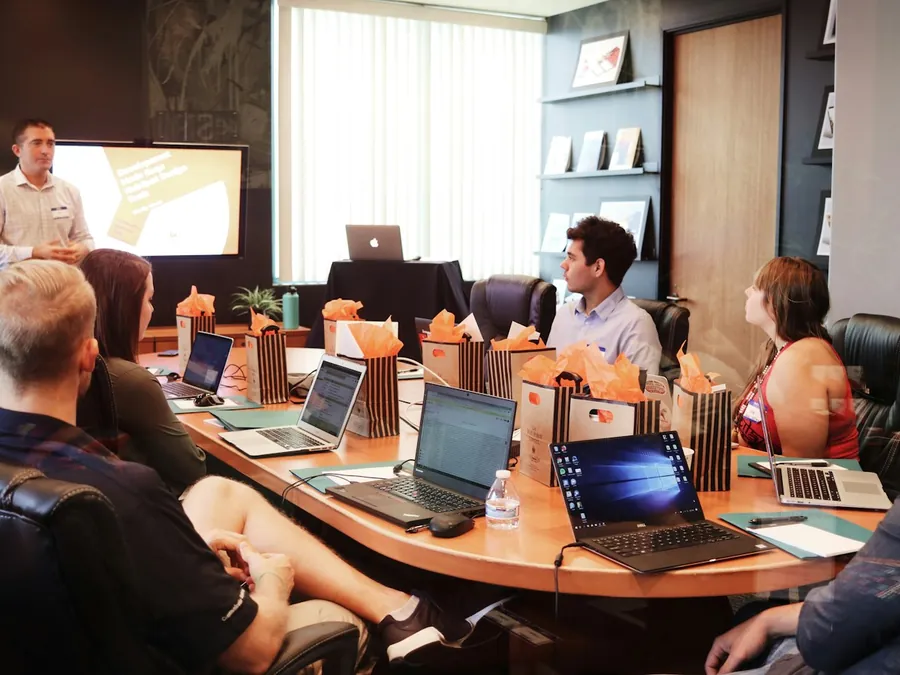 Un equipo sigue una presentación con sus computadores en una sala de reuniones